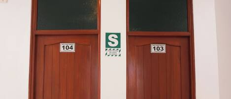 Two wooden doors with numbers 104 and 103, a potted plant, and a sign with the letter 'S'.