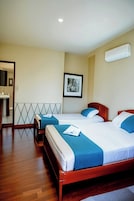 Habitación de hotel con dos camas, un espejo grande, un cuadro enmarcado en la pared y una lámpara en el techo.