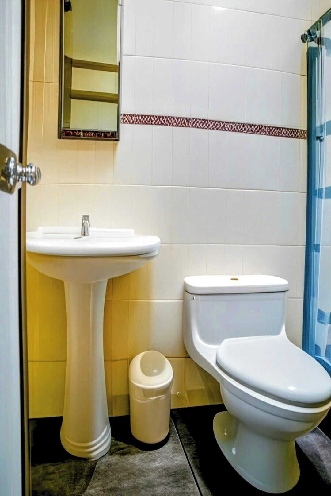 Et badeværelse med et pedalvask, toilet og en lille skraldespand.
