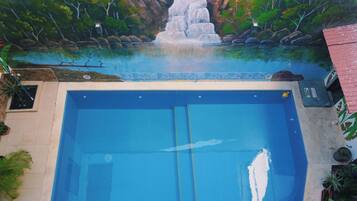 Una piscina con un mural que muestra una cascada y árboles.
