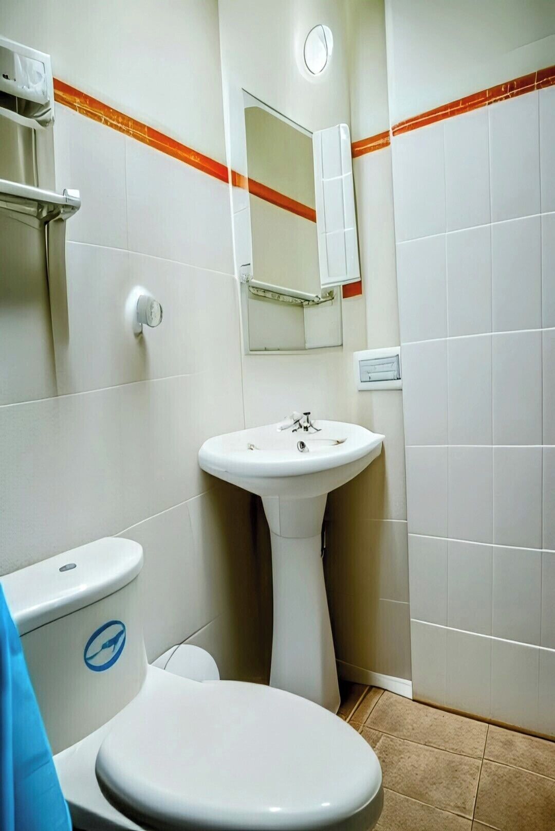 Een badkamer met een wit wastafelmeubel, een toilet en een spiegel boven de wastafel.