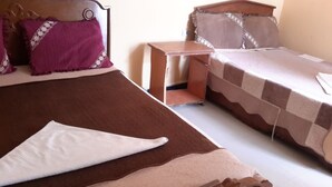 A hotel room with two beds, a wooden headboard, a nightstand, and a white pillow. - Liya Guest House  (Addis Ababa)
