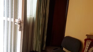 A room with a partially open door, a chair, and a curtain. - Liya Guest House  (Addis Ababa)