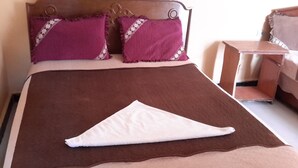A bed with a brown bedspread and two purple pillows with floral trim. - Liya Guest House  (Addis Ababa)
