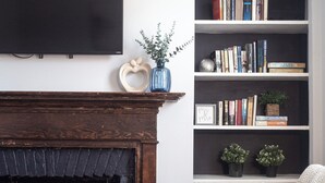 Un salon avec une cheminée, une bibliothèque et un téléviseur fixé au mur.