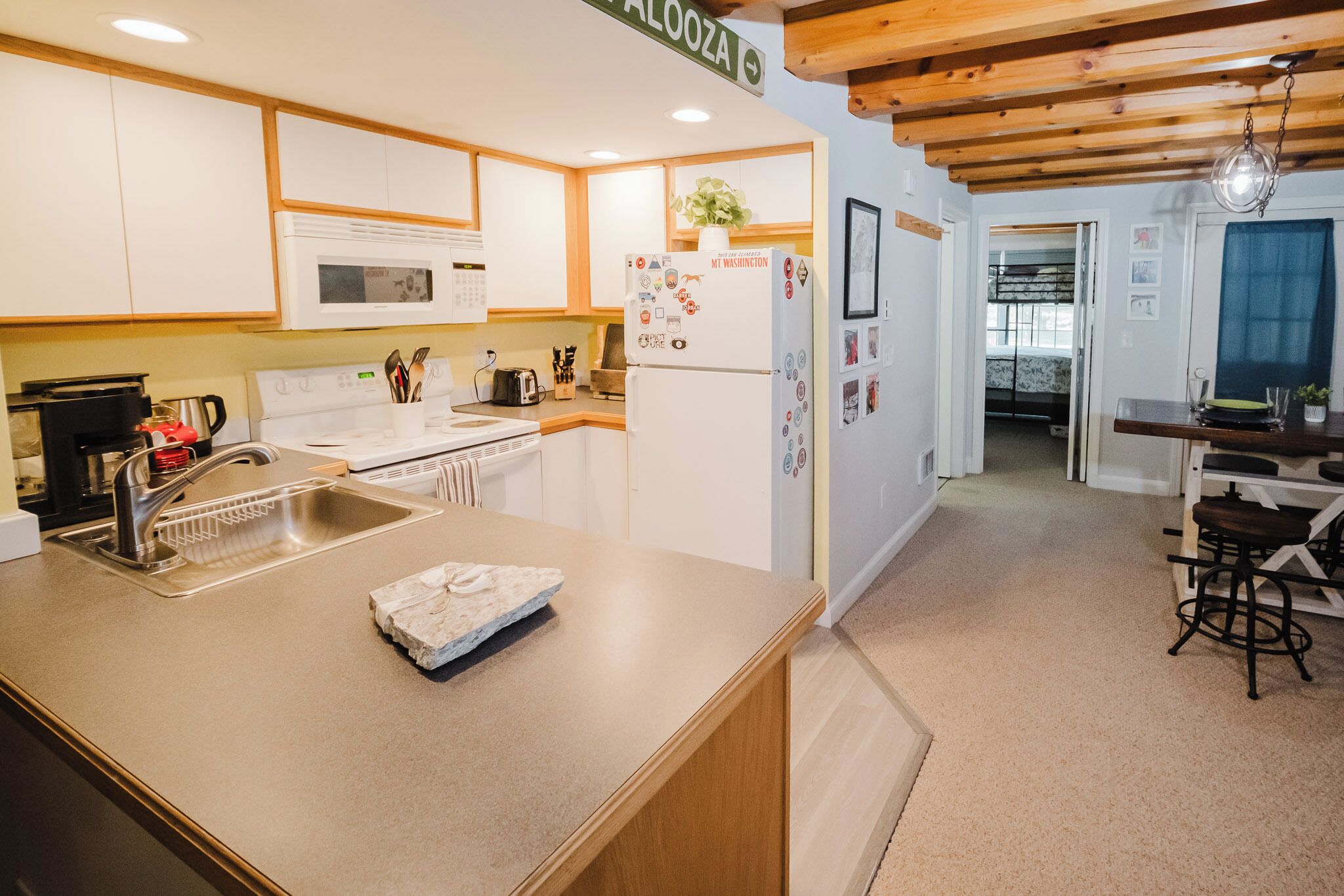 A modern kitchen with white cabinets, a stainless steel sink, and a wooden ceiling.