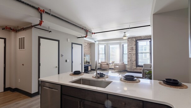 A modern kitchen with a large island, dark cabinetry, and a visible dishwasher.