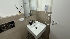 A modern bathroom with a white sink, a mirror, a hairdryer, and a bottle of hand soap. - Best Bnb Barbadori (Florence)