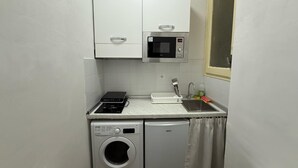 A compact kitchenette with a microwave, a small sink, and a washing machine. - Best Bnb Barbadori (Florence)