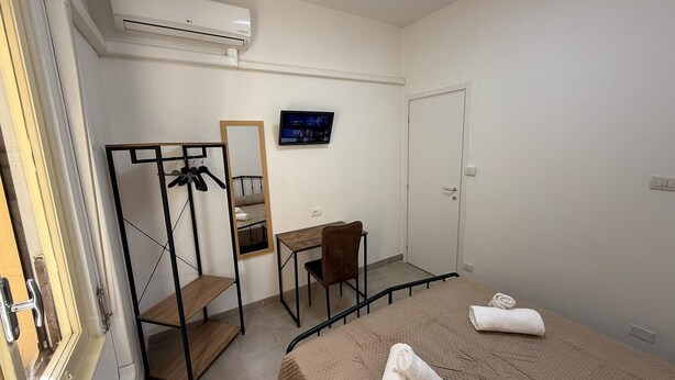 A hotel room with a bed, a desk, a chair, a mirror, and an air conditioning unit. - Best Bnb Barbadori (Florence)