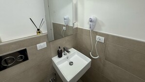 A bathroom with a white sink, a mirror, a hairdryer, and a bottle of hand soap. - Best Bnb Barbadori (Florence)