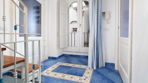 A hallway with blue-tiled flooring, white walls, and a wooden staircase. - Marescala vacation - Tarantino House, cozy apartment in the historic center (Sorrento)