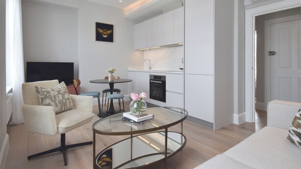Un salon moderne avec une table basse en verre, un canapé et un téléviseur.