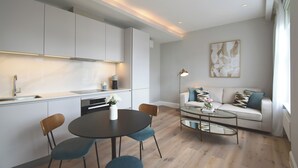 Une cuisine moderne avec des meubles blancs, une table à manger avec des chaises, un canapé et une table basse.
