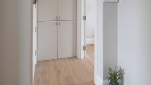 Un couloir doté d’un plancher en bois, de murs blancs et d’une porte donnant sur une autre pièce.