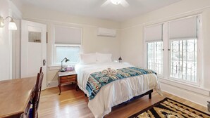 A bedroom with a bed, a ceiling fan, a nightstand, a desk, and a window with blinds. - Inviting Remodeled Guest House in Central Nob Hill (Albuquerque)