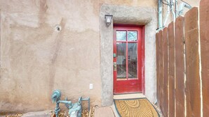 A narrow entrance with a red door, a small porch area, and a wooden fence. - Inviting Remodeled Guest House in Central Nob Hill (Albuquerque)