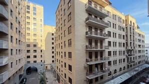Ein mehrstöckiges Wohngebäude mit Balkonen, einem überdachten Parkbereich und Blick auf die Straße.