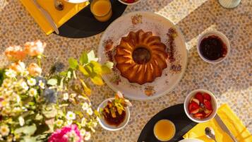 Een gedekte tafel met een bundt cake, koffie, thee, fruit en een bloemstuk.