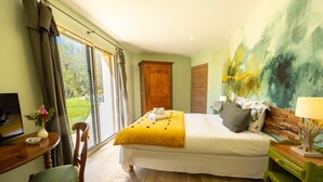 A bedroom with a bed, a desk, a chair, a TV, and a painting on the wall. - Bed and breakfast Le Rucher des Combes - Chambre Vézère (Fleurac)