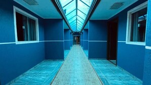 A corridor with a skylight ceiling, blue walls, and a tiled floor. - Pousada Centaurus (Alto Paraíso de Goiás)