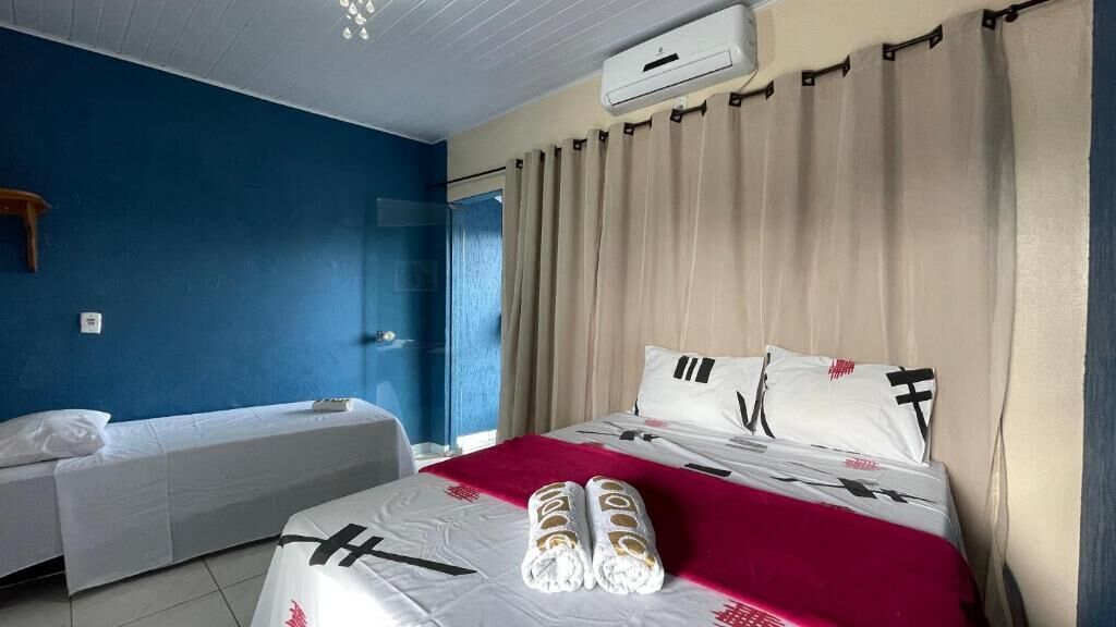 Quarto de hotel com uma cama, uma cama de solteiro e um aparelho de ar condicionado.