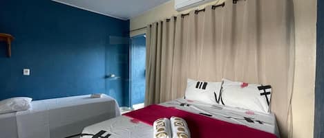 A hotel room with a bed, a smaller bed, and an air conditioning unit.