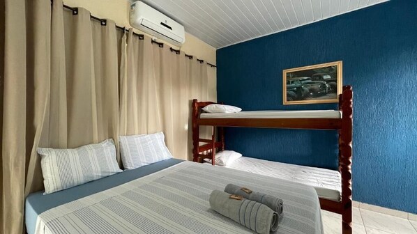 A room with a bunk bed, a single bed, and a painting on the wall. - Pousada Centaurus (Alto Paraíso de Goiás)