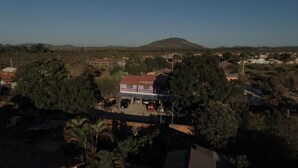 A residential area with a house featuring a red roof, surrounded by trees and a hilly landscape in the background. - Pousada Centaurus (Alto Paraíso de Goiás)