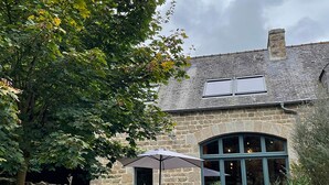 A stone house with a patio, a table, two chairs, and an umbrella. - La Grange du Manoir (eco-cottage for 2–4 people) (Le Vieux-Marché)