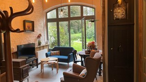 A cozy living room with a blue sofa, a wooden coffee table, and a fireplace. - La Grange du Manoir (eco-cottage for 2–4 people) (Le Vieux-Marché)