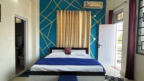 Un dormitorio con cama, ventilador de techo, ventana con cortinas y una puerta.