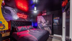 Une chambre à coucher sur le thème de Star Wars, avec un grand lit, des affiches de Star Wars et un ventilateur de plafond.