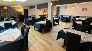 A restaurant with multiple tables and chairs, a patterned wall, and pendant lighting.