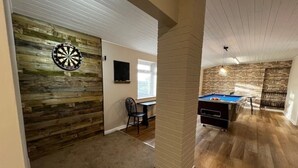 Una habitación con dardos, una mesa de billar y un muro de madera.