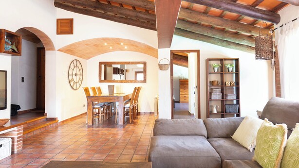 A living room with a sofa, a dining area with a table and chairs, and a kitchen area with a shelf and a hanging light fixture. - Bel House fantastic property located in the exclusive urbanization Res.Begur (CT)