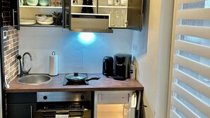 Une cuisine compacte équipée d’un four encastré, d’une machine à café et d’un évier.