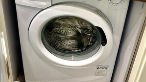 Un espace buanderie compact comprenant un lave-linge et un évier.