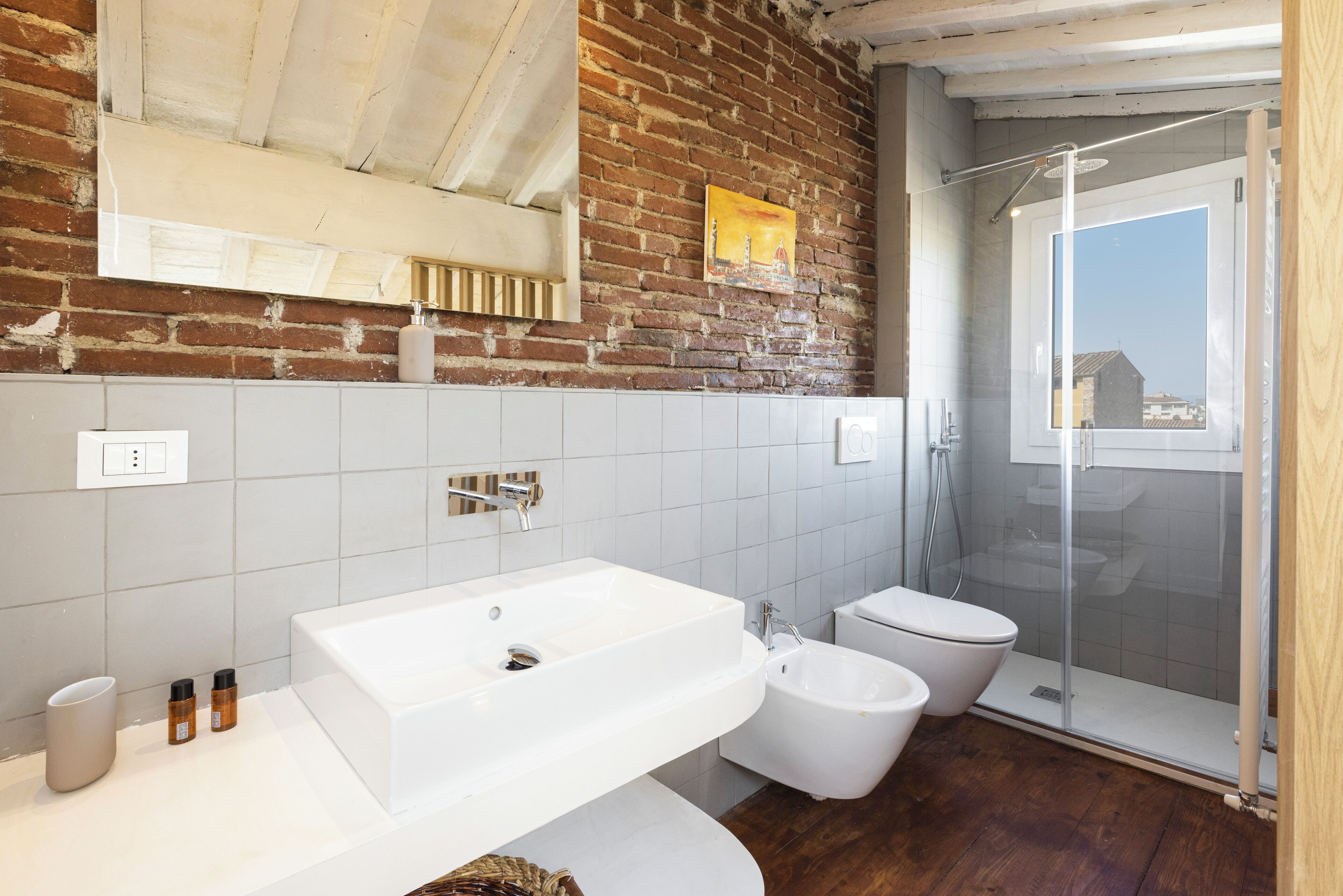 A modern bathroom with a white sink, a bidet, and a glass-enclosed shower.