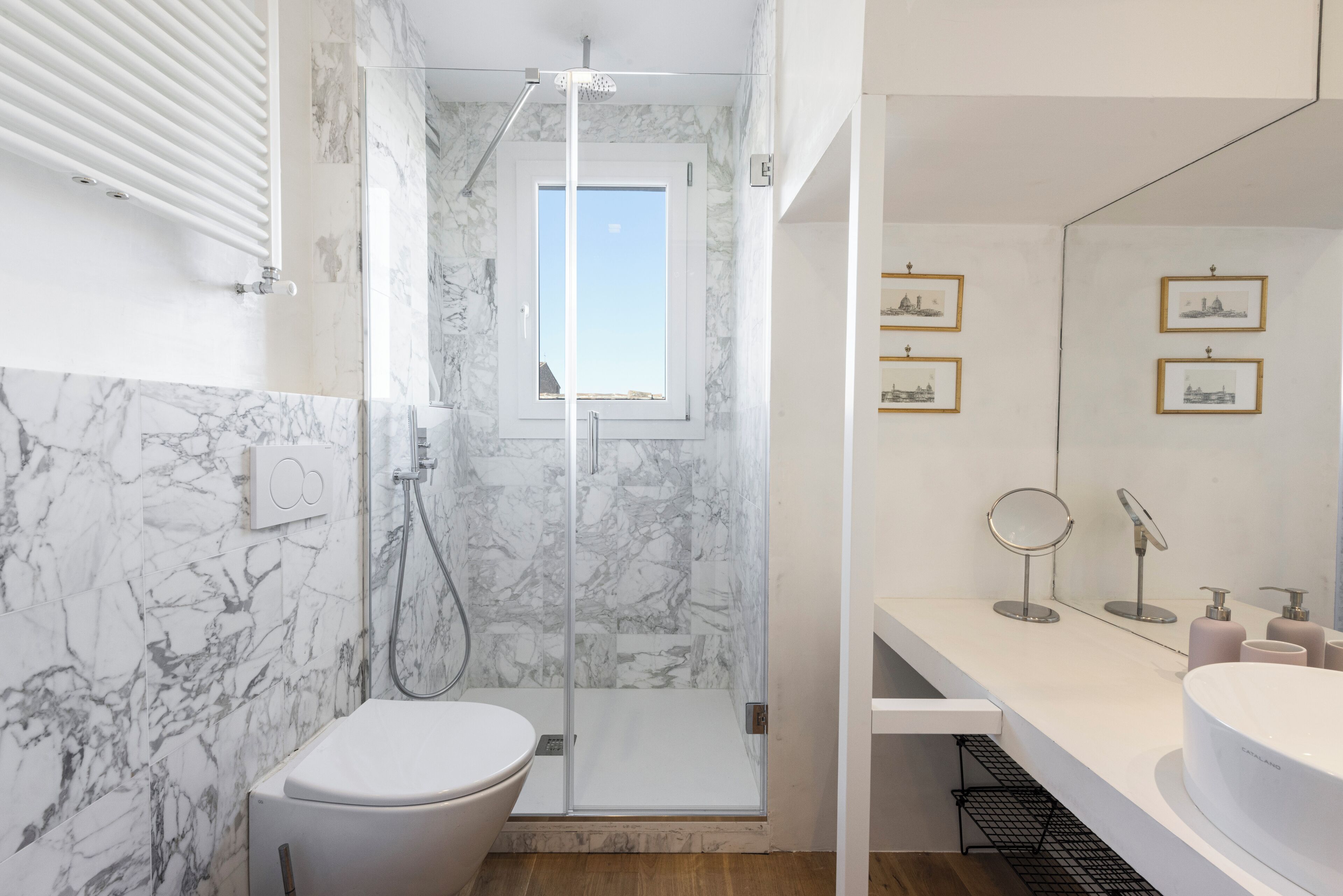 A modern bathroom with a glass-enclosed shower, a toilet, and a vanity with a sink and mirrors.