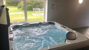 Un jacuzzi con vista a un jardín y sillas al aire libre.