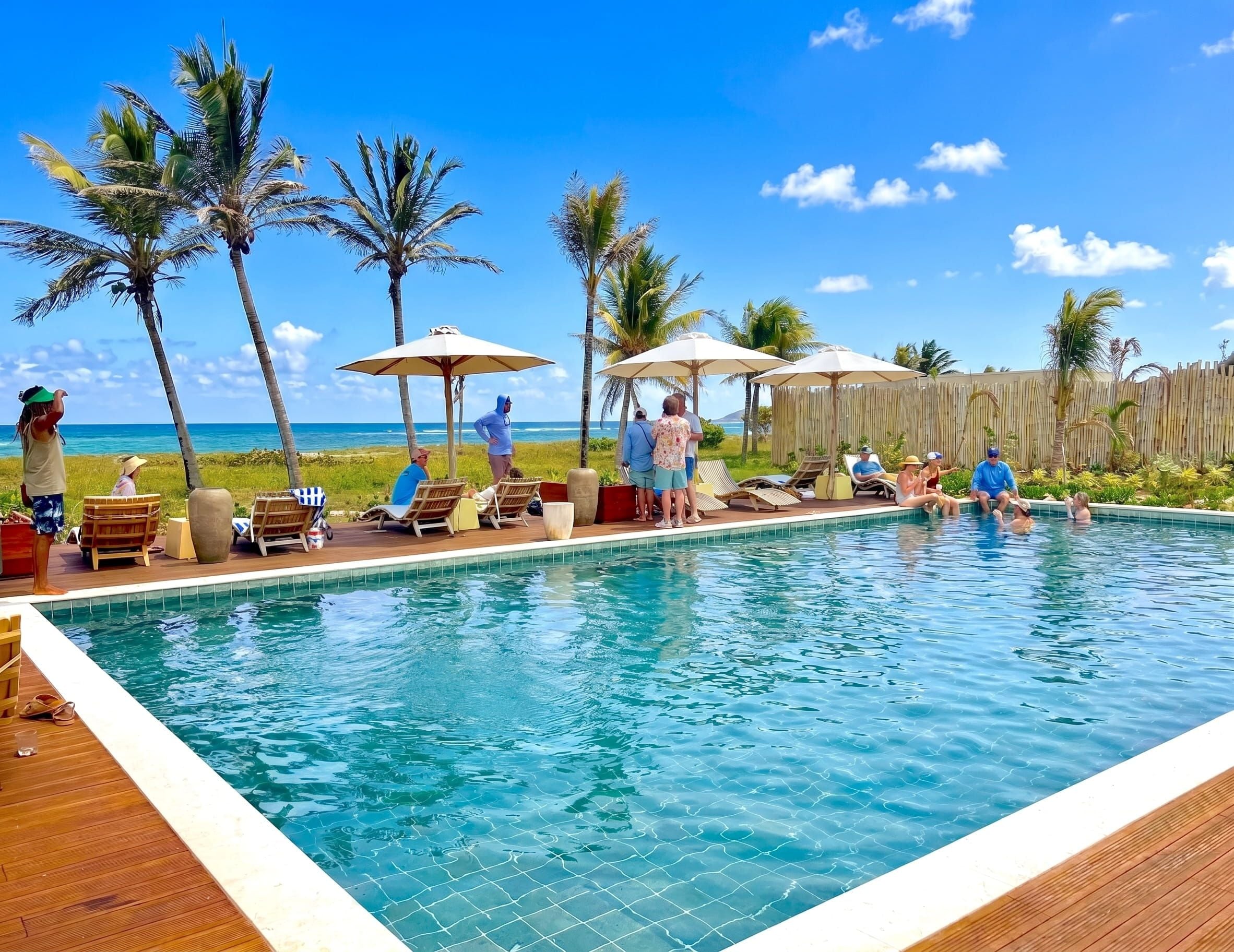 Ein Poolbereich mit Liegestühlen und Sonnenschirmen, mit Blick auf einen Strand.