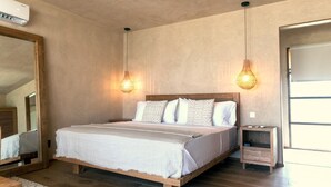 A bedroom with a wooden bed, two bedside lamps, a nightstand, and a large mirror. - Windward Mayreau Resort (Mayreau Island)