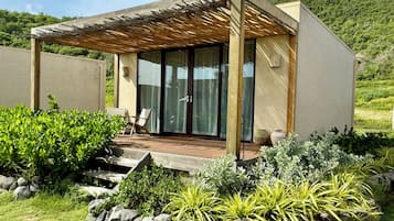 Une maison moderne dotée d’une terrasse en bois, d’un patio couvert et d’une porte vitrée donnant sur une pièce.