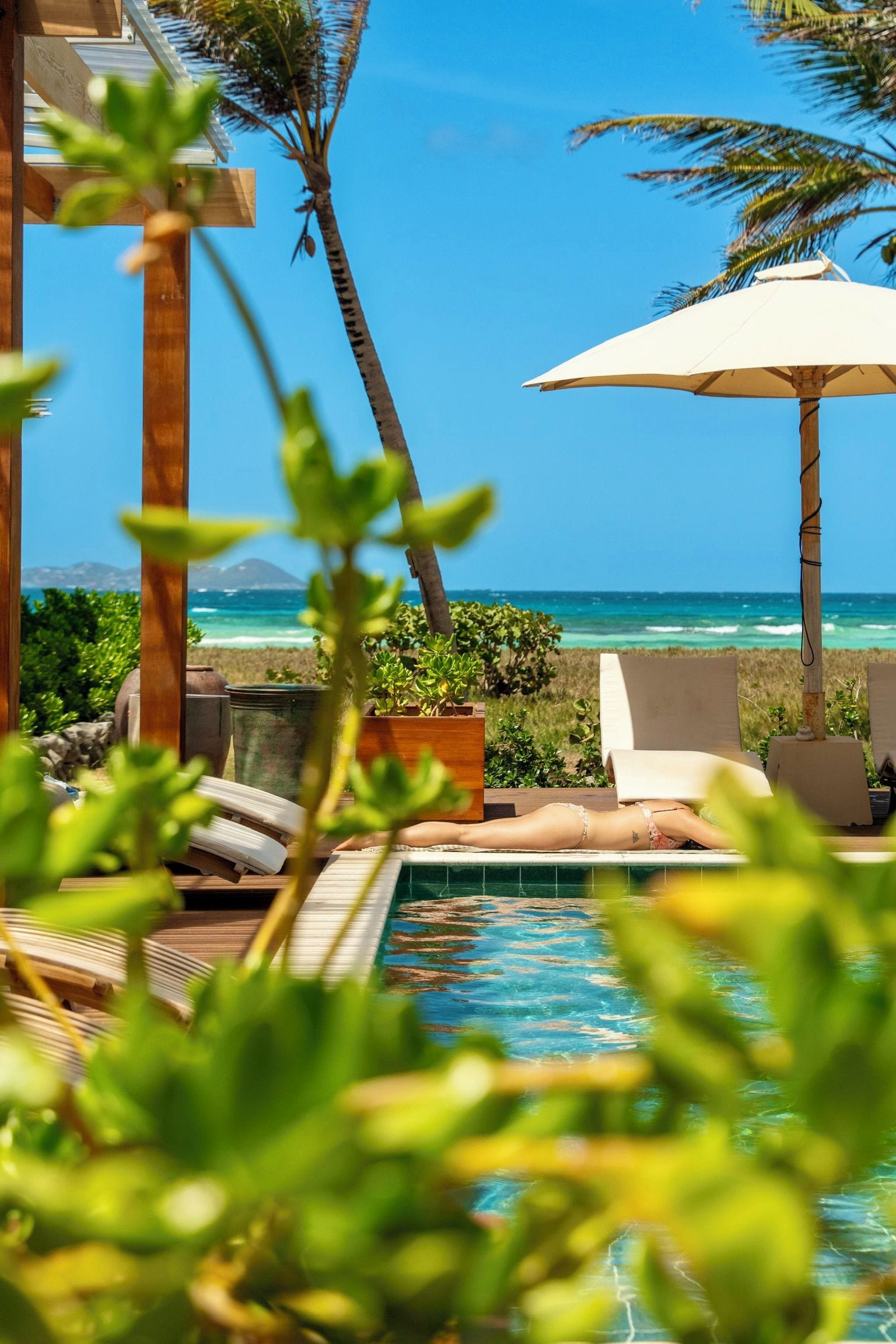 A pool area with lounge chairs and a view of the ocean.