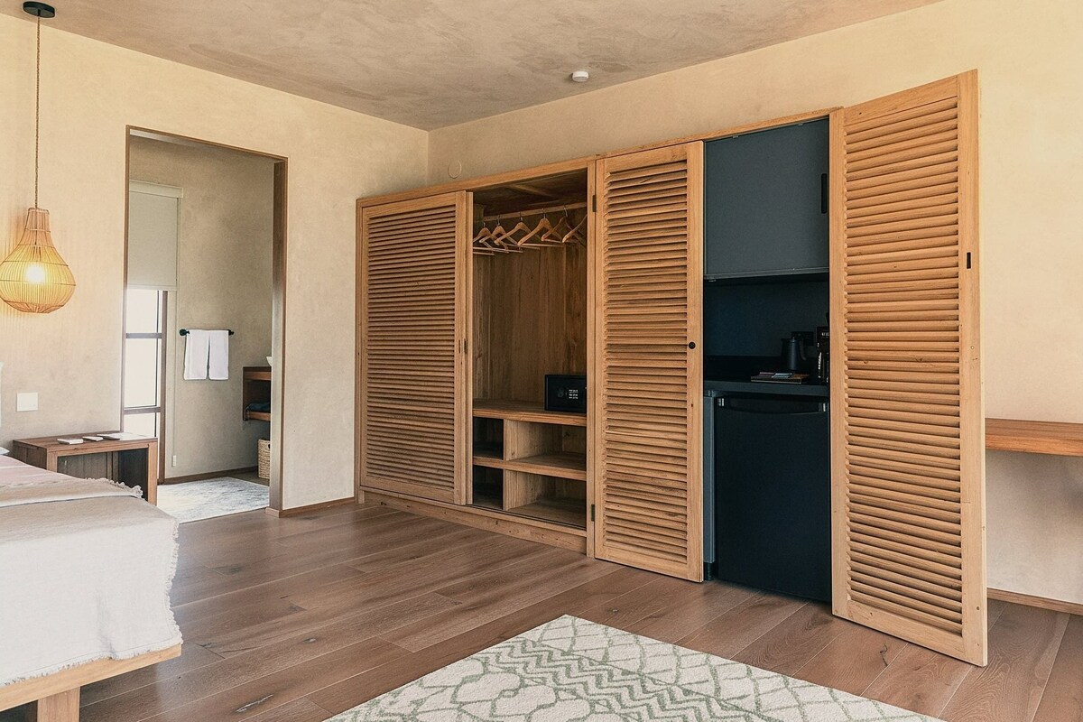 A bedroom with wooden flooring, a bed, a wardrobe with sliding doors, and a hanging light fixture.
