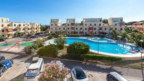 A residential building with a swimming pool, parked cars, and a playground. - Sardinia Re - Lido 125 (Alghero)