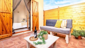 A cozy outdoor seating area with a sofa, a table with drinks and a plant, and a wooden fence in the background. - Sardinia Re - Lido 125 (Alghero)