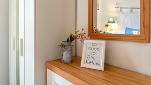 A wooden console table with a framed quote, a metal vase with dried flowers, and a mirror reflecting a bed and nightstand. - Sardinia Re - Lido 125 (Alghero)