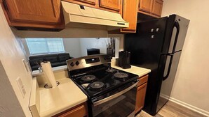 Une cuisine avec des meubles de rangement en bois, un poêle noir et un réfrigérateur noir.